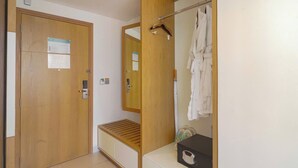 A bathroom with a wooden door, a bench, a mirror, and a towel rack. - Signature Luxury Village (Da Nang)