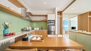 A modern kitchen with a wooden table, chairs, and a dining area. - Signature Luxury Village (Da Nang)
