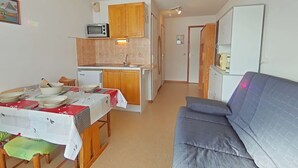 A compact living space with a kitchenette, a dining area, and a seating area. - Studio near slopes, balcony with Aravis view (Le Grand-Bornand)