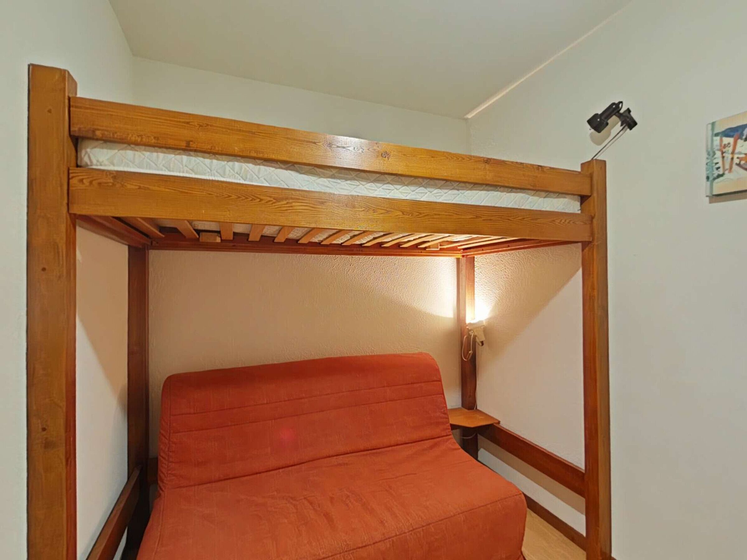 Letto a castello con struttura in legno e materasso.