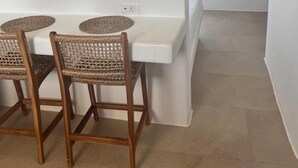 A dining area with a white table and four wicker chairs, a ceiling fan, and a TV mounted on the wall. - Sunrise Villa Sea View up to 4 pax (Ano Mera)