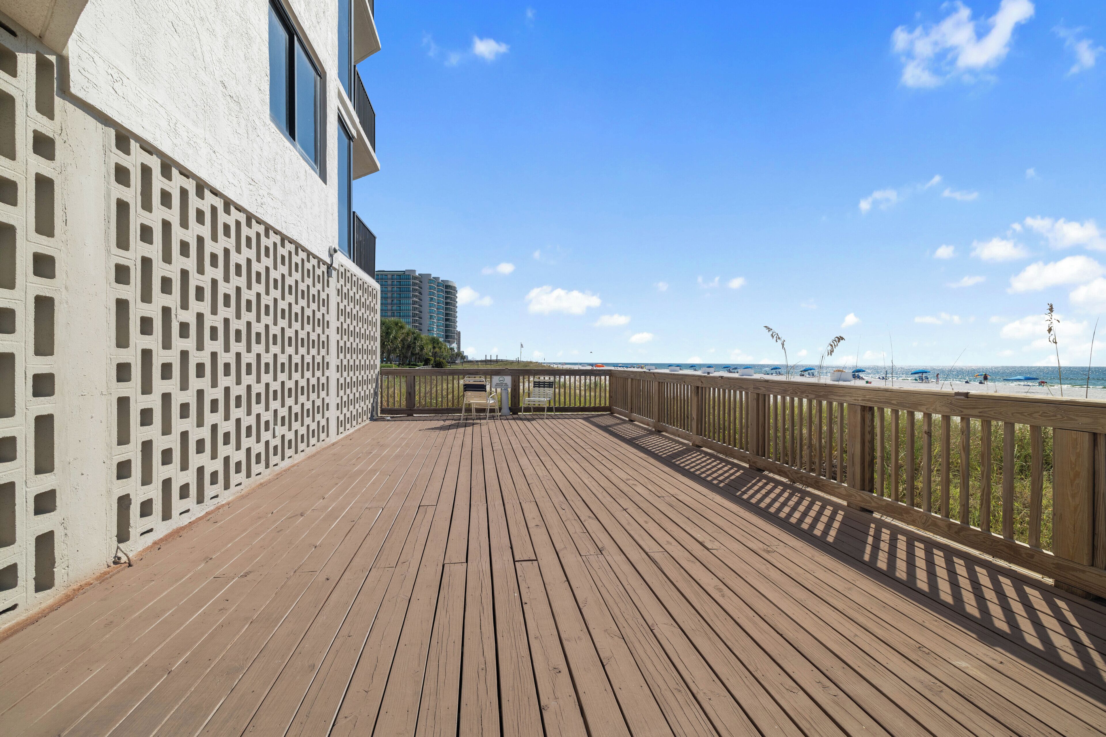 A wooden deck with a railing overlooking a beach.