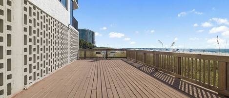 A wooden deck with a railing overlooking a beach.