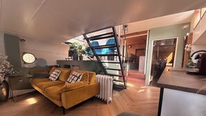 Ein modernes Wohnzimmer mit einem gelben Sofa, einem Couchtisch, einer Heizung und einer Treppe, die zu einer anderen Ebene führt.