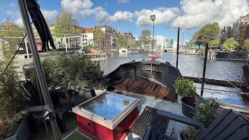 A riverside view with a boat dock, a red structure, and a bridge in the background.