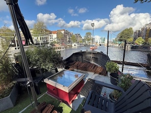 Uitzicht op een rivier met een steiger, een rode constructie en een brug op de achtergrond.