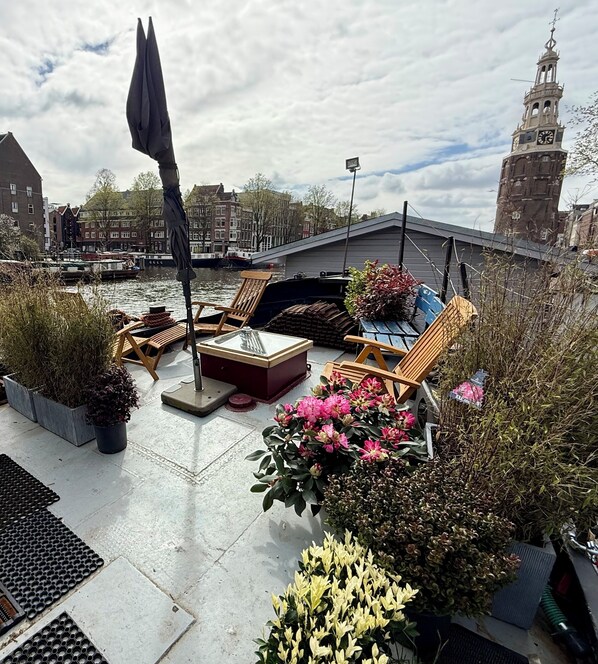 Une terrasse sur le toit, aménagée avec des sièges, des plantes en pot et offrant une vue sur un bâtiment historique.