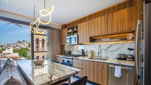 Cozinha moderna com armários de madeira, bancada de mármore e forno embutido.
