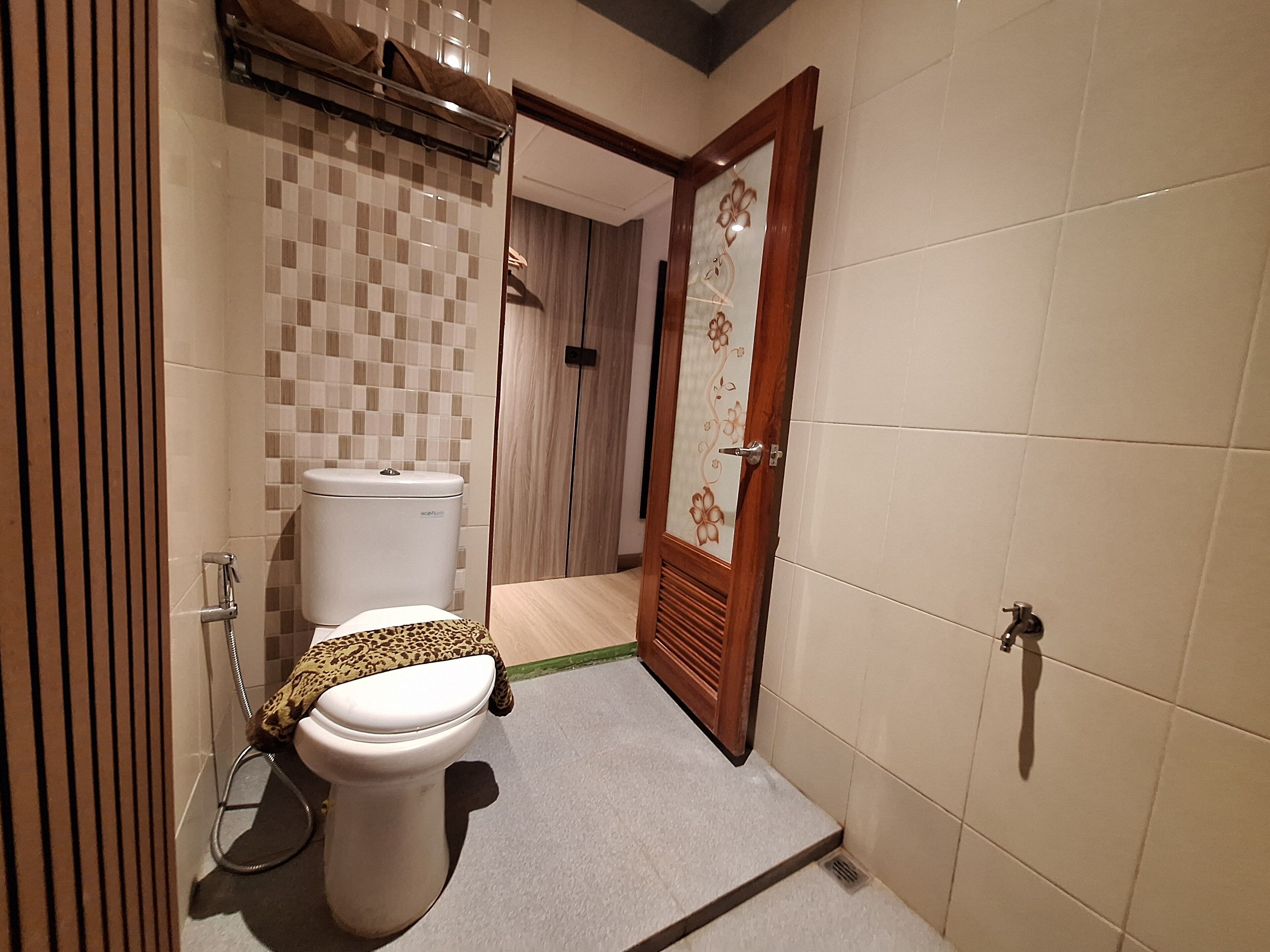 A bathroom with a toilet, a shower area, and a tiled wall.