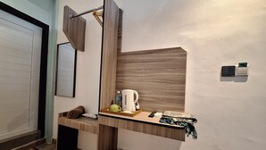 A compact bathroom with a wooden vanity, a towel, a trash bin, and a mirror.