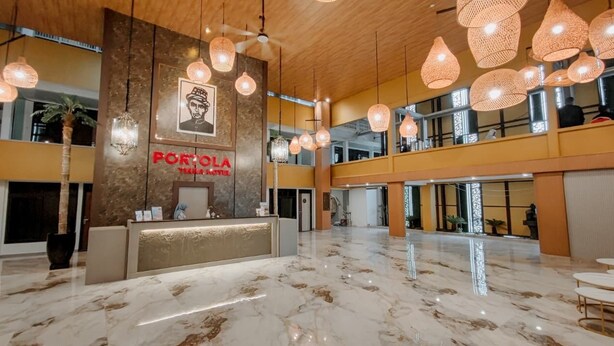 A spacious lobby with a reception desk, hanging pendant lights, and a marble floor.