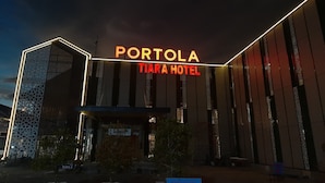 Η εξωτερική όψη του ξενοδοχείου Portola Tiara, με τον μοντέρνο σχεδιασμό του και τις φωτεινές επιγραφές.
