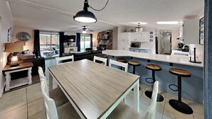 Una cucina moderna con isola centrale, sgabelli da bar bianchi e un tavolo da pranzo con sedie.