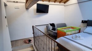 A bedroom with a bed, a TV, a staircase, and a child's play area. - House Sant 'Angelo (Acquapendente)