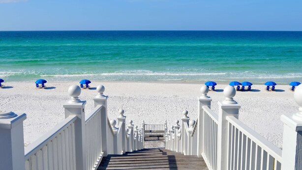 A wooden staircase leading to a beach with white railings and blue umbrellas. - Seaside Guest Home 3 Mins to Beach & Seaside Ave, Prime Seaside Location (Santa Rosa Beach)