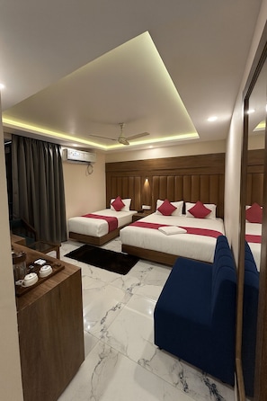 A hotel room with two beds, a ceiling fan, a coffee table, and a large mirror. - The Heritage Chinar by Ackee Tree (Srinagar)
