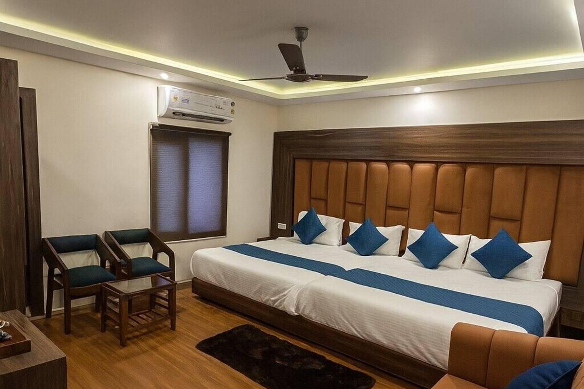 A hotel room with a bed, a sofa, a desk, and a ceiling fan.