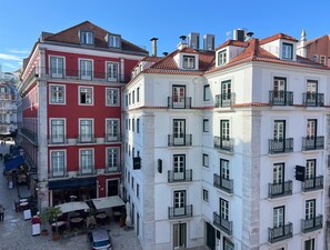 Un hotel con varios pisos, balcones y un patio con mobiliario exterior.
