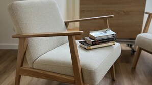 A modern armchair with a light fabric, positioned on a wooden floor. - Rossio Garden Suites (Lisbon)
