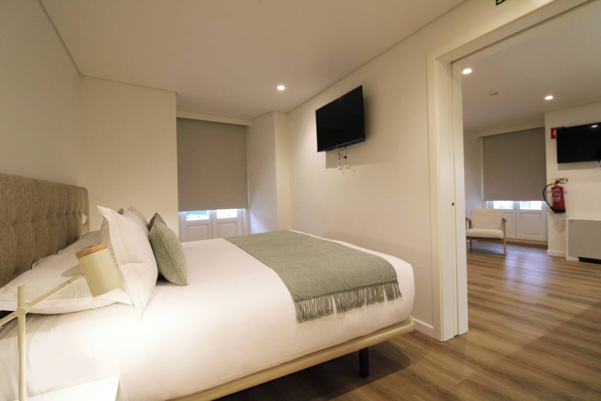 Une chambre à coucher moderne avec un grand lit, un téléviseur à écran plat fixé au mur et un plancher en bois.