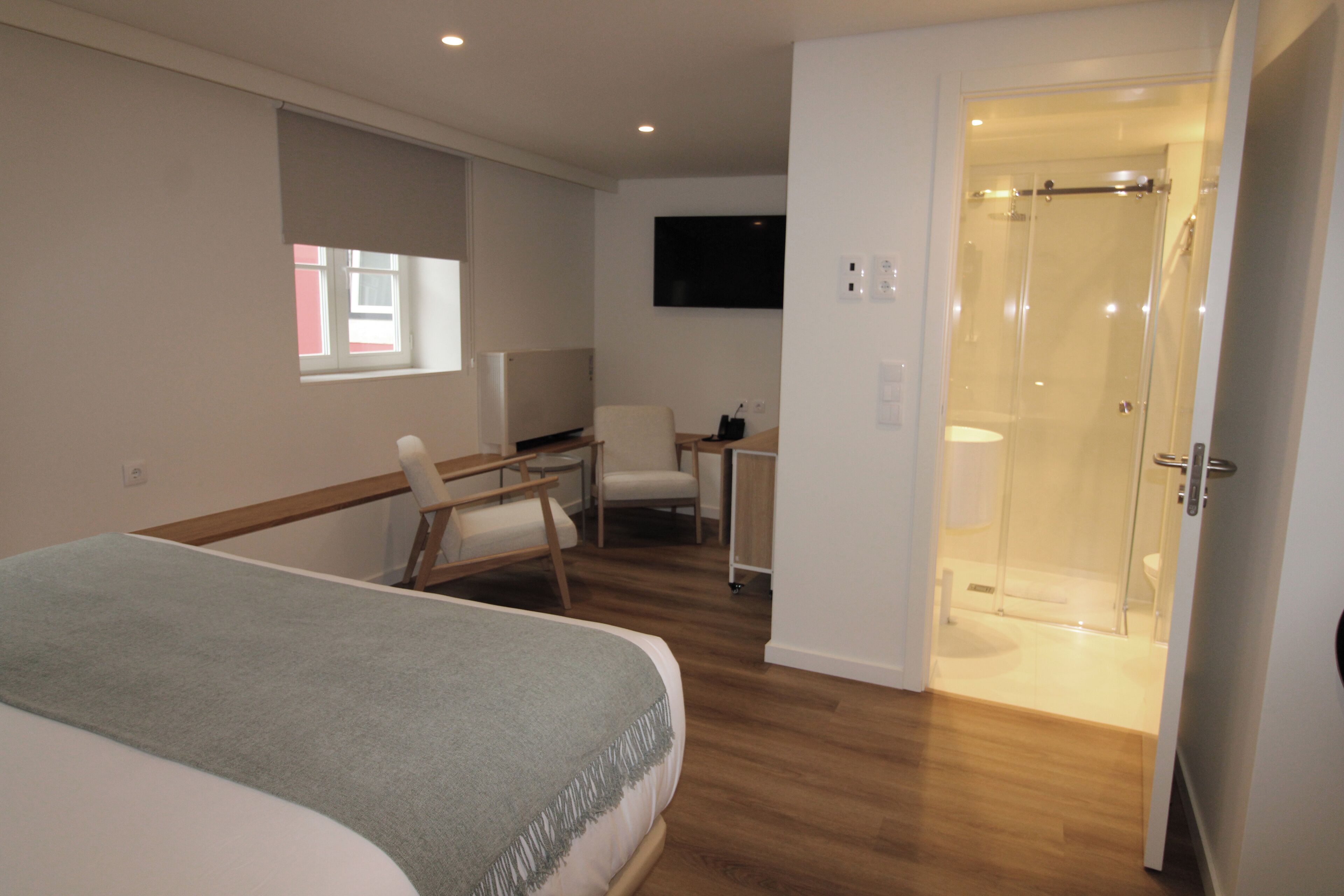 Ein Hotelzimmer mit Bett, Schreibtisch, Stuhl, Fernseher und Duschbereich.