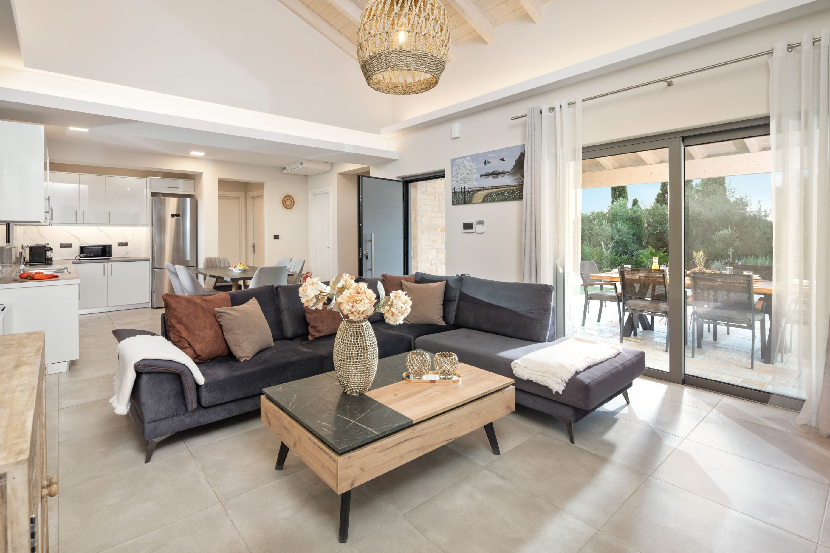 A modern living room with a sofa, coffee table, and a dining area with a table and chairs.