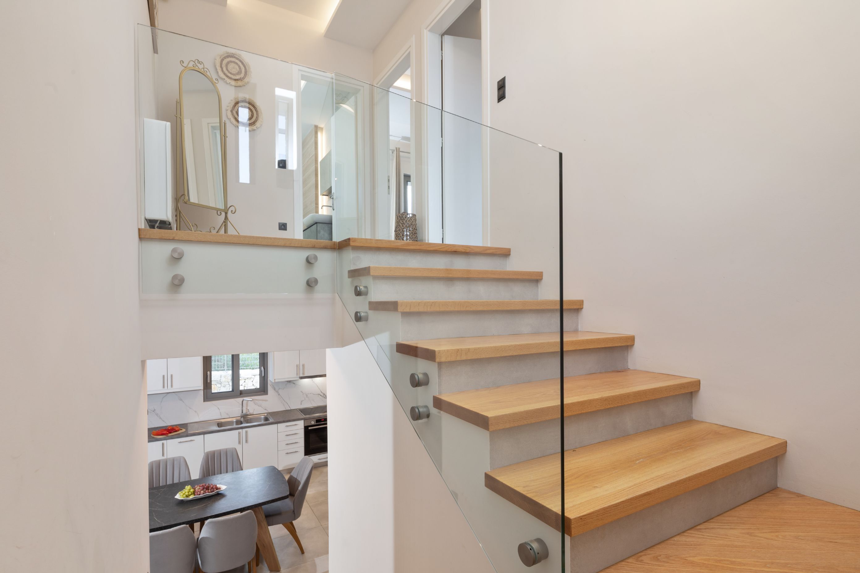 Una moderna scala con ringhiere in vetro e gradini in legno che conduce a un piano superiore.