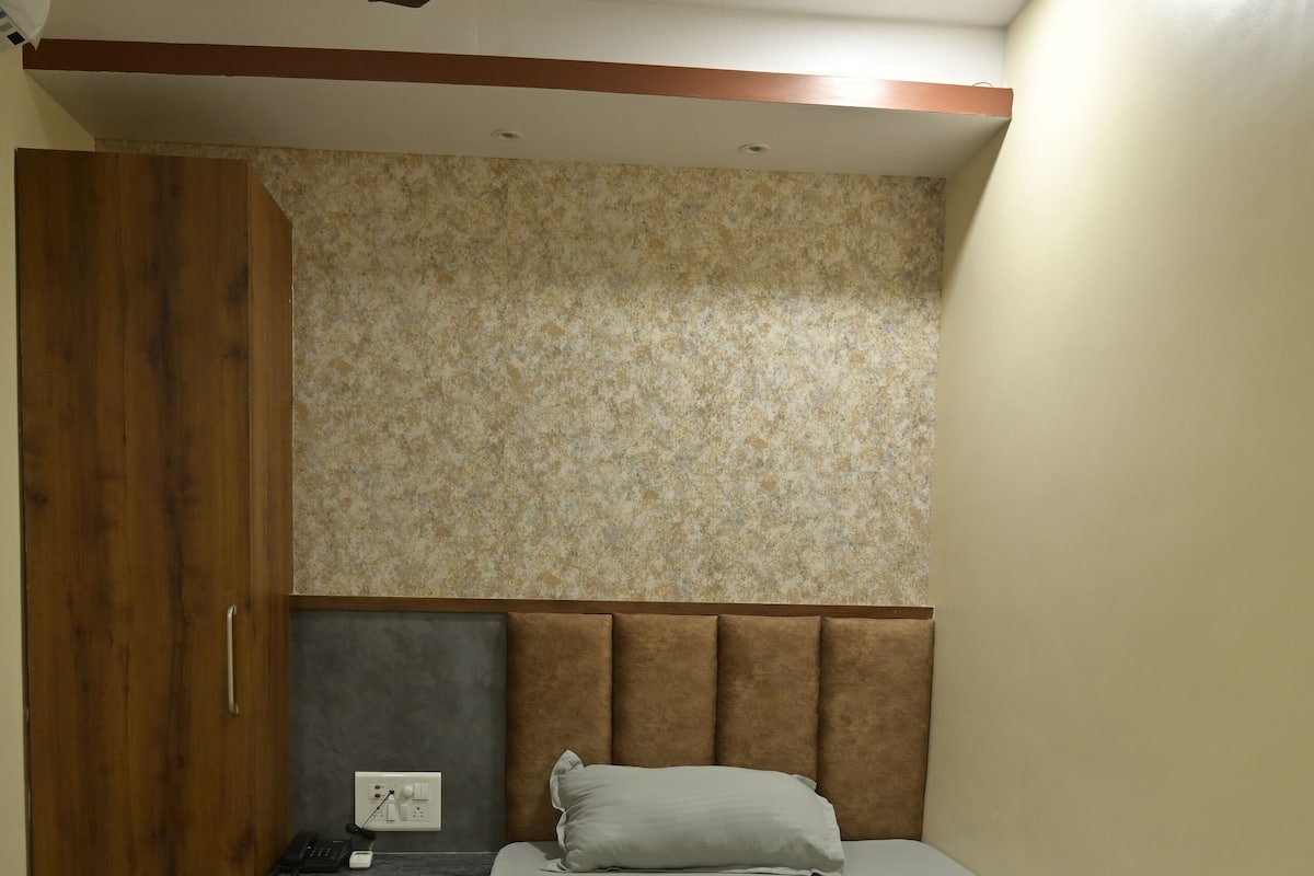 A bedroom with a bed, a nightstand, a wardrobe, a ceiling fan, and a textured wall.