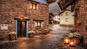 A stone building with a blue door and windows, a cobblestone street, and a mountain in the background. - Jacuzzi, Kamin, Grill und spektakuläre Aussicht by Interhome (Las Ventas)