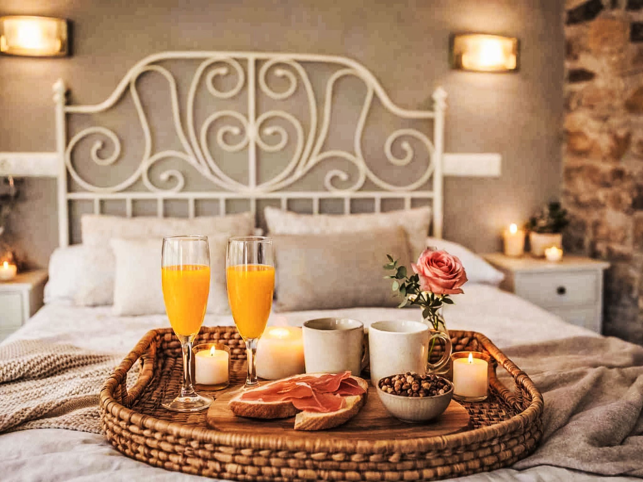 A neatly made bed with a decorative headboard, a tray with breakfast items, and a vase with a single rose.