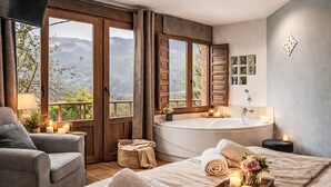 A bedroom with a large window, a bathtub, a sofa, and a bedside table with candles. - Jacuzzi, Kamin, Grill und spektakuläre Aussicht by Interhome (Las Ventas)