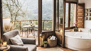 A room with a large window, a bathtub, a chair, a table, and a basket. - Jacuzzi, Kamin, Grill und spektakuläre Aussicht by Interhome (Las Ventas)