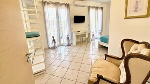 Ein Hotelzimmer mit einem Bett, einem Schreibtisch, einem Stuhl, einem Fernseher und einem Fenster mit Vorhängen.