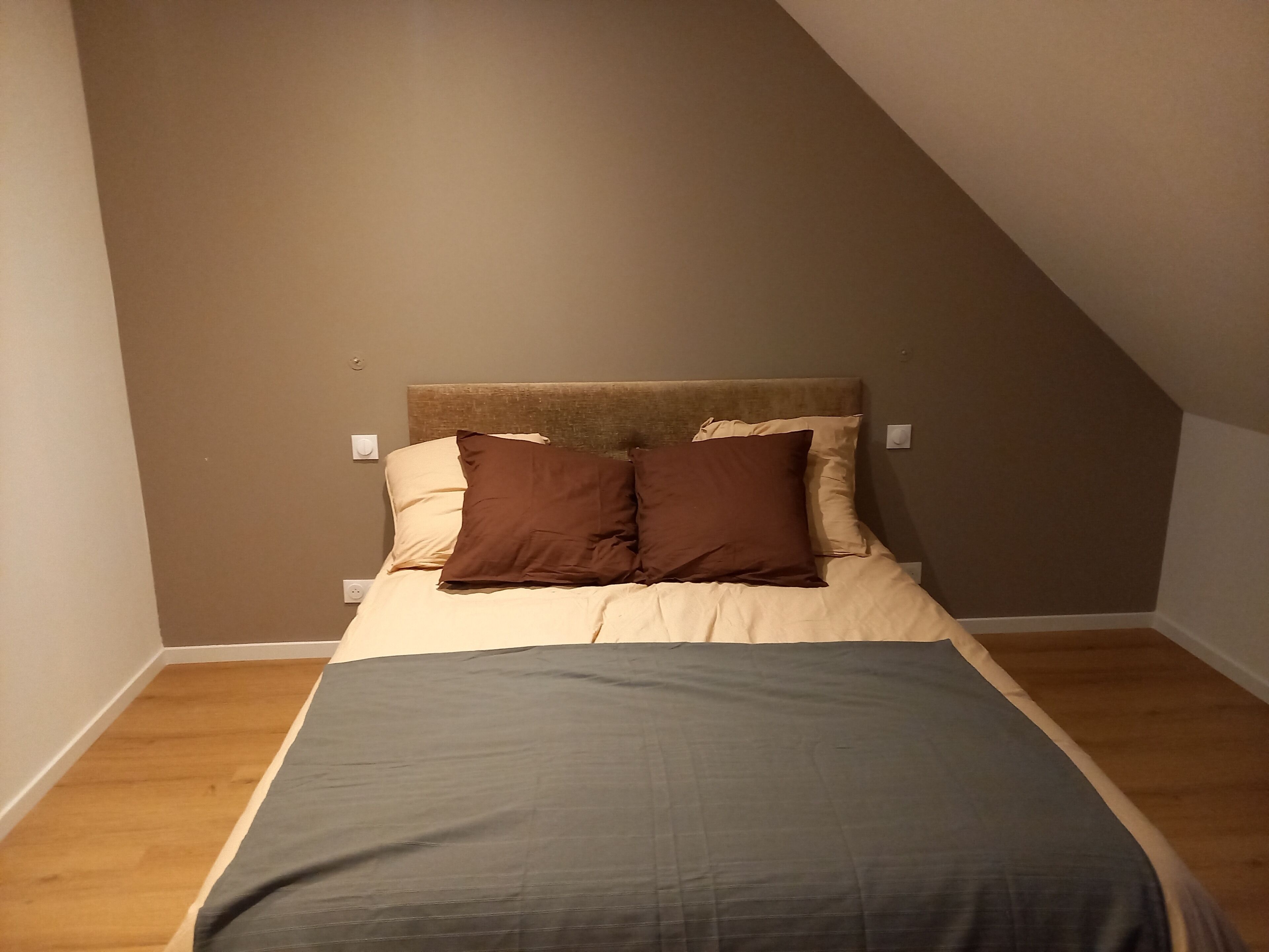 Ein Schlafzimmer mit einem Bett, zwei Kissen, einem Kopfteil und Holzboden.