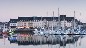 A marina with multiple boats docked, a waterfront building with shops, and a calm water reflecting the boats. - House Raguenez 4.5 km from the sea - Near Paimpol (Pleumeur-Gautier)