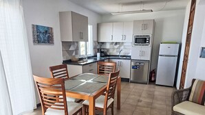 Eine kompakte Küche mit Essbereich, ausgestattet mit einer Mikrowelle, einem Kühlschrank und einer Kaffeemaschine.