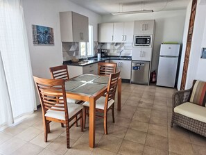 Eine kompakte Küche mit Essbereich, ausgestattet mit einer Mikrowelle, einem Kühlschrank und einer Kaffeemaschine.