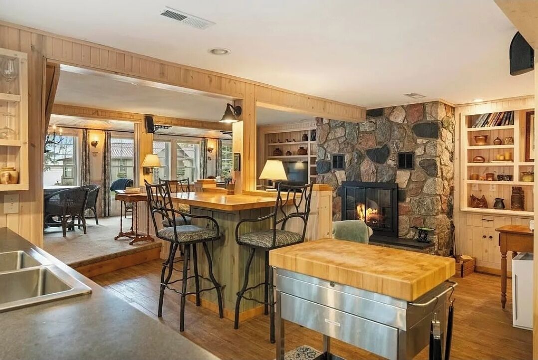 Une cuisine chaleureuse avec un mur en pierre, des tabourets de bar en bois et une cheminée.