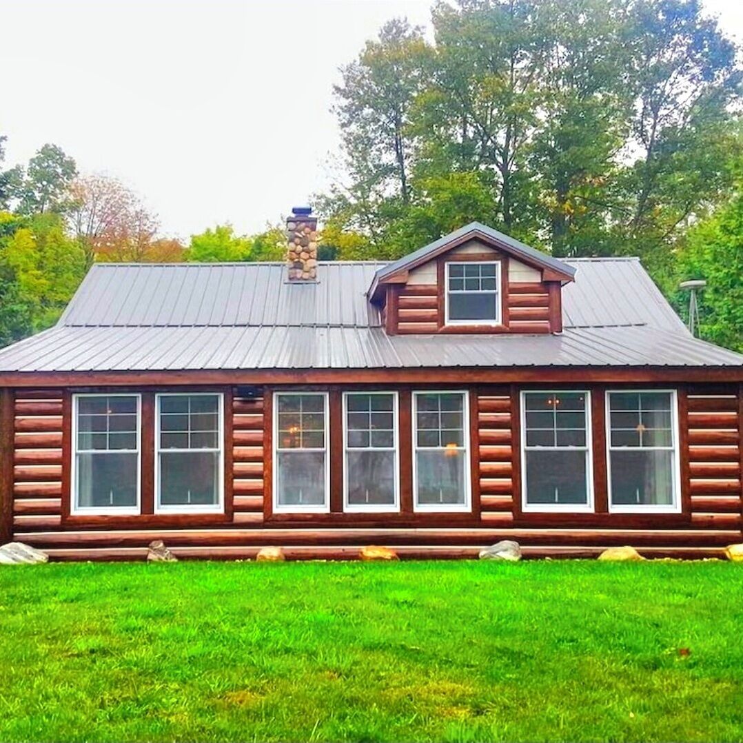 A log cabin with a metal roof and multiple windows.