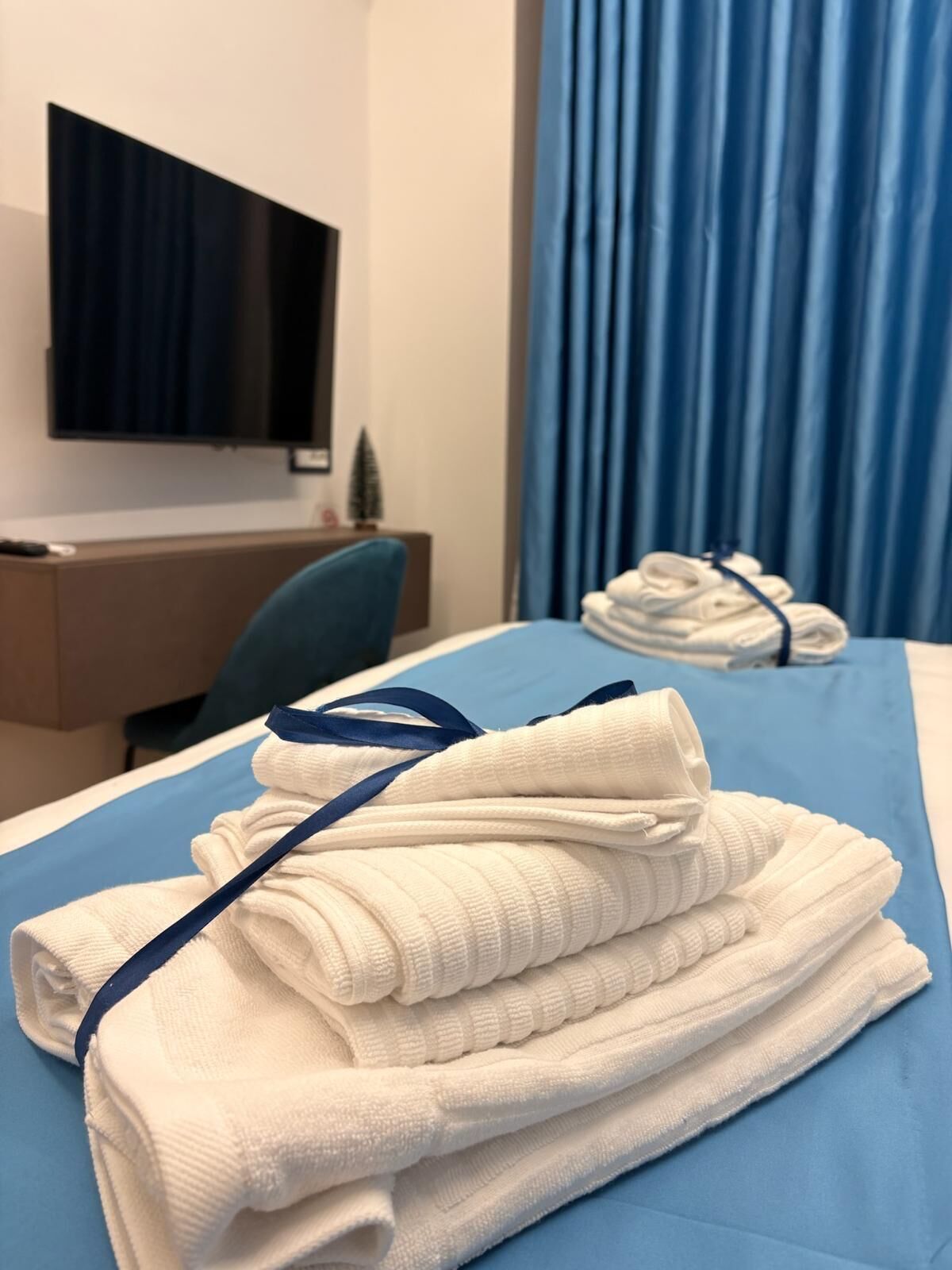 Een opgemaakt bed met gevouwen handdoeken en een blauw dekbed in een hotelkamer.