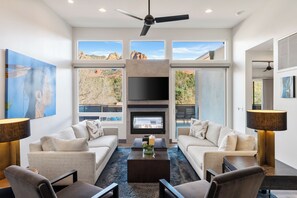 A modern living room with a fireplace, two sofas, a coffee table, and a TV. - 180 DEGREE VIEWS OF THE RED ROCKS W/3 MASTER EnSuite BEDROOMS, VIEWS GALORE!!! (Sedona)