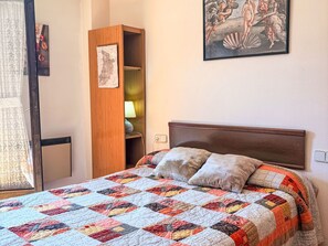 Een slaapkamer met een bed, een houten garderobe, een kaart aan de muur en een lijst met kunstwerk.