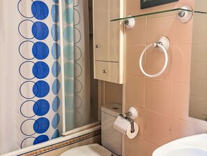 Een badkamer met toilet, een douchecabine van glas, een handdoekhouder en een kast.