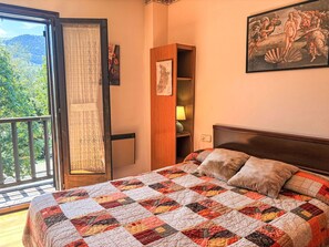 Ein Schlafzimmer mit einem großen Bett, einem Holzschrank, einer Karte an der Wand und einem Balkon mit Blick auf Bäume.