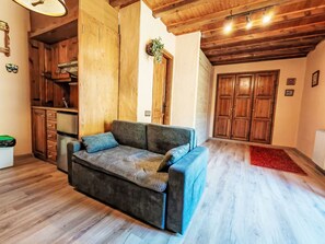 Ein gemütliches Wohnzimmer mit einer Couch, Holzschränken und einer Decke mit freiliegenden Balken.