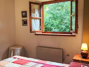 A bedroom with a bed, a bedside table with a lamp, a window with curtains, and a radiator. - Wohnung mit Garten Isard 4 Vall de Boí by Interhome (Caldes de Boi)