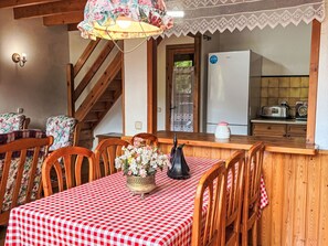 A dining area with a checkered tablecloth, wooden chairs, a vase of flowers, and a staircase. - Geräumige Maisonette mit Kamin Isard 2 Vall de Boí by Interhome (Caldes de Boi)