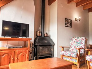 A living room with a TV, a fireplace, wooden furniture, and a floral chair. - Geräumige Maisonette mit Kamin Isard 2 Vall de Boí by Interhome (Caldes de Boi)