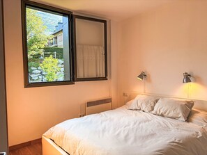 A bedroom with a bed, a window with a view of greenery, and a wall-mounted lamp. - Gemütliche und komfortable Wohnung Aüt 2 Vall de Boí by Interhome (Caldes de Boi)
