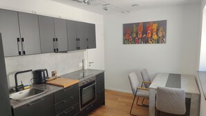 Una cocina moderna con armarios grises, horno empotrado y comedor con mesa y sillas.